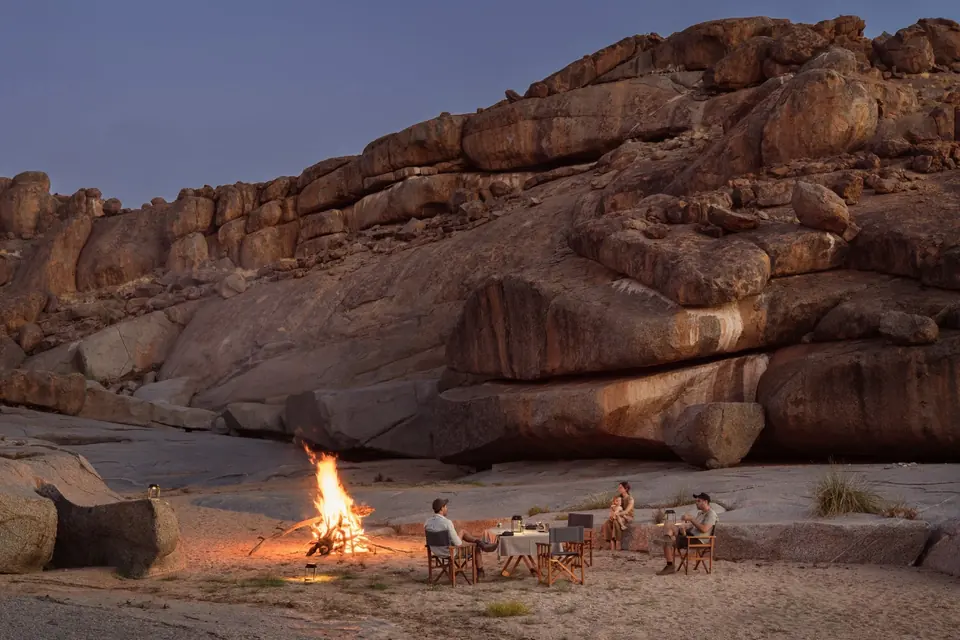 Family gathered around a campfire under the stars at Sandfontein, Namibia