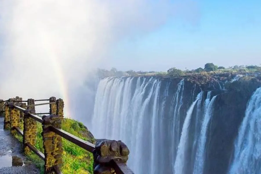Victoria Falls in full flow with a rainbow in the spray, seen from the cliffside path near Kasane, Botswana