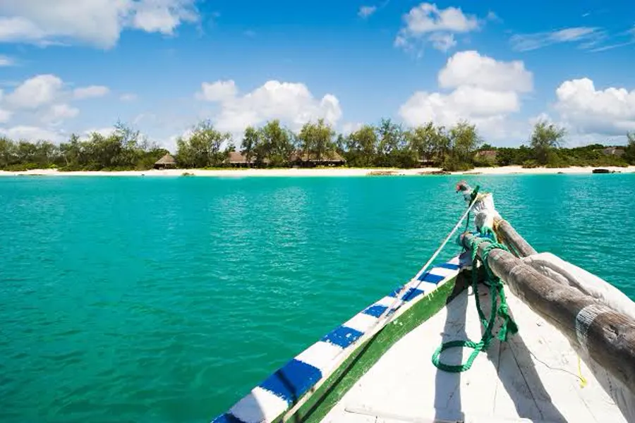 View from the bow of a traditional wooden dhow approaching a palm-fringed uninhabited island in the Quirimbas Archipelago