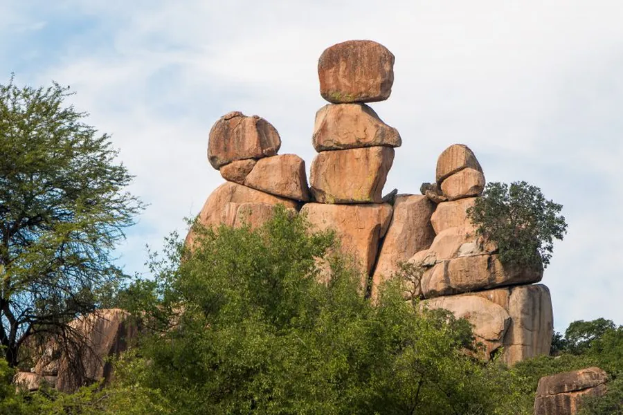 Balancing granite boulders known as Mother and Child rocks among green trees in the Matobo Hills, Zimbabwe