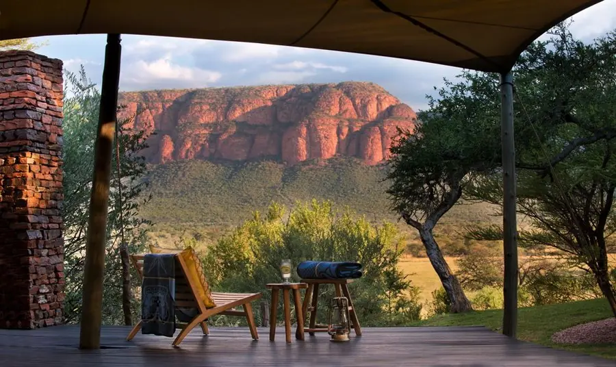 View from a shaded lodge deck to red sandstone cliffs and bushveld in the Waterberg, South Africa
