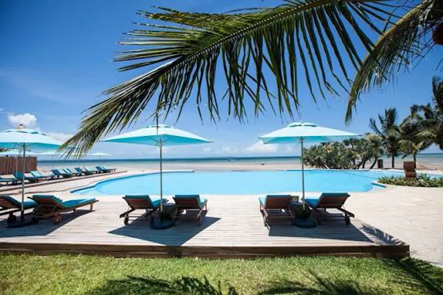 Beachfront pool with turquoise umbrellas and sun loungers looking out to the Bazaruto Archipelago from Vilanculos