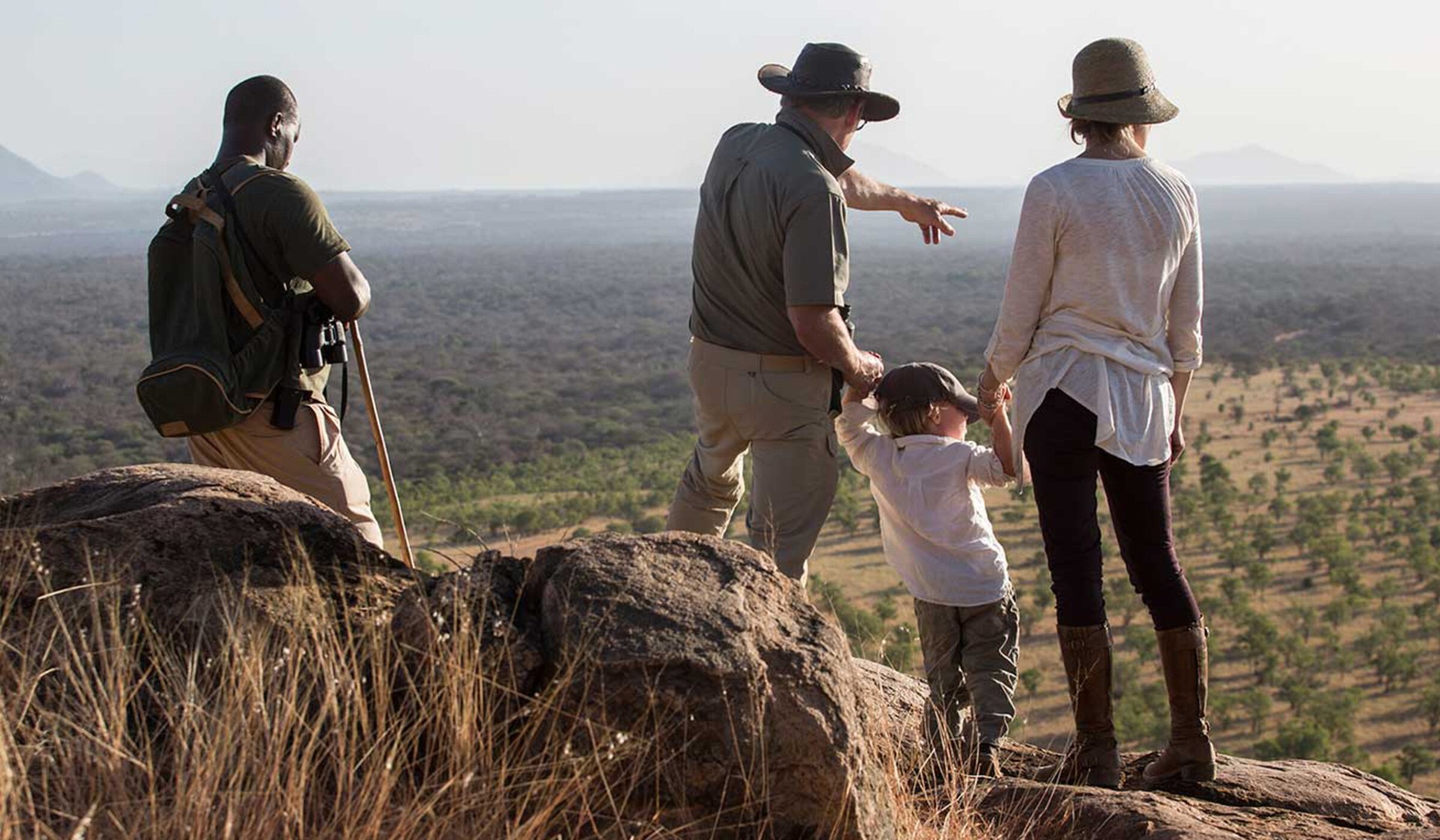 Family on a walking safari with a Kenyan guide overlooking the savannah